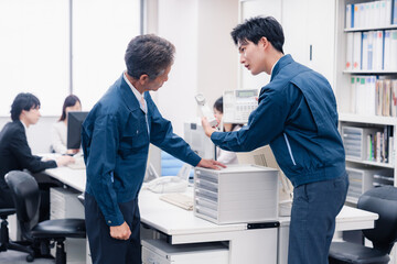 オフィスで電話機のメンテナンスをする作業員の男性