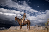 Cowboy riding horse in mountain wilderness outfitter