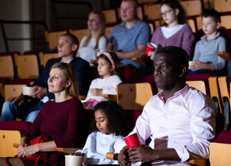 Wall Mural - International family enjoys watching comedy in a cinema hall