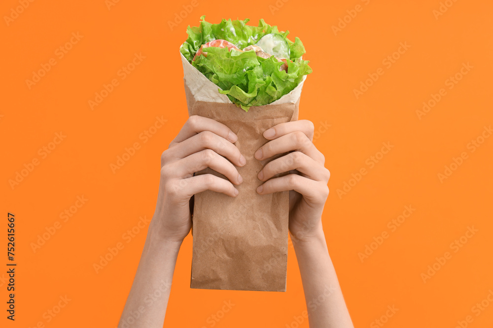 Hands with tasty doner kebab on orange background