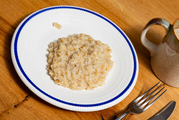 Wall Mural - Boiled oatmeal porridge served in white plate. Concept of diet food