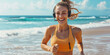 Smiling adult woman with headphones running on the beach