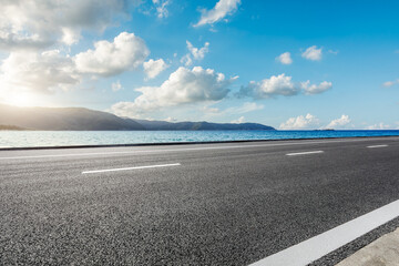 Wall Mural - Asphalt highway road and blue lake with mountain nature landscape under blue sky