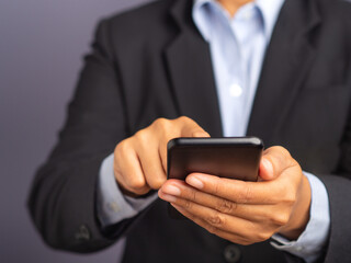 Wall Mural - businessman using a smartphone while standing on a black background.