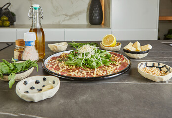 Canvas Print - Mouth watering carpaccio made with fresh, high-quality ingredients laid out on a sleek black marble countertop