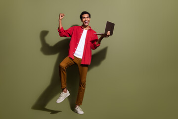 Wall Mural - Full length photo of funny excited man dressed red shirt enjoying online sale modern device empty space isolated green color background
