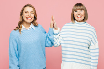 Wall Mural - Elder parent mom 50s years old with young adult daughter two women together wearing blue casual clothes meeting together greeting giving high five isolated on plain pink background Family day concept