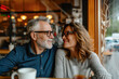© olga - Portrait of cheerful senior couple sitting at table in cafe. Happy old couple talking and enjoying  at cafe.