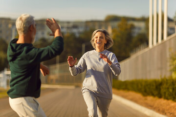 Wall Mural - Happy senior couple share a moment of joy, exchanging high fives during run or jog in the city park. Captures the running and outdoor together jogging bring joy to this active and vibrant senior duo.