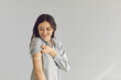 © Studio Romantic - Happy smiling young lady showing arm after flu or Covid-19 vaccine injection. Woman promoting coronavirus vaccination and immunization campaign on light gray empty blank text studio background