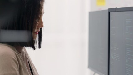 Wall Mural - a young woman programmer intensely focused on developing software on a computer screen in a bright o