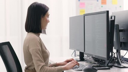 Wall Mural - professional female programmer is focused on writing and analyzing code across multiple screens in t