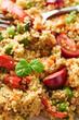 Vegan warm salad made with couscous, tomatoes, green beans, mint, roasted carrots and sweet peppers. Couscous with vegetables, close up. Variation of Tabbouleh Salad.