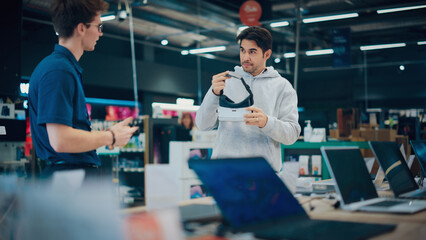 Wall Mural - Young Man Having a Conversation with a Salesperson in a Electronics Store while Trying Out a Virtual Reality Device. Customer Wishes to Buy a VR Set. Shopper Explores Latest Options with Expert Advice