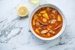 Bowl of manhattan clam chowder on a white marble background, horizontal shot with space, above view