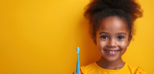 happy black kid girl child holds toothbrush in hand on yellow isolated background. Pediatric dentistry for brushing teeth