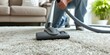 Individual using vacuum cleaner to clean carpeted surface in a home. Concept Home cleaning, Vacuuming, Household chores