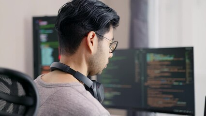 Wall Mural - over the shoulder view of a male developer analyzing a sophisticated script on his monitor, embodyin