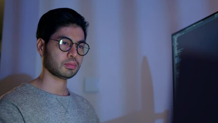 Wall Mural - the soft glow of the monitor illuminates a male developer's face, captured in a moment of thoughtful
