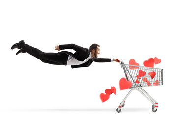 Canvas Print - Businessman flying and holding a shopping cart with red hearts