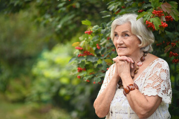 Wall Mural - Portrait of happy senior woman posing at forest