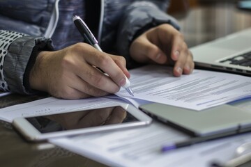 Business professional working on documents with a smartphone and laptop.