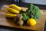 Fototapeta Kuchnia - Banany, brokuł, kiwi i cytryna. Świeże owoce i warzywa leżą na desce do krojenia. Produkty przeznaczone do zdrowej diety.
