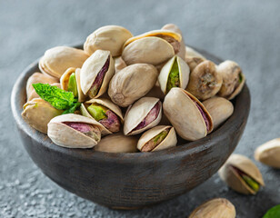 Wall Mural - Delicious pistachios in bowl on grey textured table