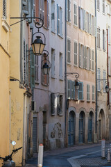 Romantic backstreet road alley in historic old town downtown Toulon, France with Mediterranean style house building facades and old little piazzas fountains picturesque city scenery	