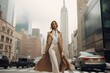 Adorned in a chic trench coat and heels, the model's confident stride exudes sophistication against a backdrop of bustling city streets and towering skyscrapers.
