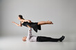 © LIGHTFIELD STUDIOS - man lying on the floor and lifting body of woman in dress during dance performance on grey backdrop