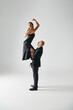 man lifting young elegant woman in black dress and high heels balancing during performance
