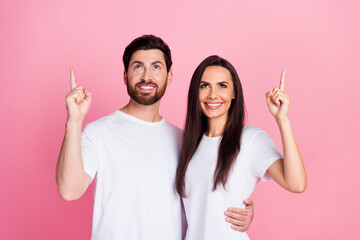 Wall Mural - Photo portrait of attractive young couple hugging point look up empty space dressed stylish white clothes isolated on pink color background