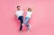 Full size photo of attractive young couple raise fists look empty space wear trendy white clothes isolated on pink color background
