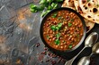 Traditional Indian Punjabi dish Dal makhani with lentils and beans in black bowl served with naan flat bread, fresh cilantro and two spoons on brown concrete rustic table top view. 