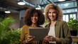 © MP Studio - Two professional women smiling and looking at a tablet together in an office setting