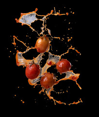 Wall Mural - tomatoes in red juice splash isolated on a black background