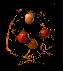 Wall Mural - tomatoes in red juice splash isolated on a black background
