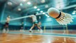 © Shaheen - A close-up shot of a shuttlecock mid-air, with players blurred in the background, showcasing the speed and intensity of a badminton match.