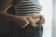 Women body fat belly. Obese woman hand holding excessive belly fat. diet lifestyle concept to reduce belly and shape up healthy stomach muscle.