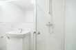 Bright white small bathroom with sink and shower. The bathroom has a large mirror with led tape, several electrical sockets and water for the washing machine.