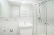 Bright white small bathroom with sink and shower. The bathroom has a large mirror with led tape, several electrical sockets, heating ladder and water with waste for the washing machine.