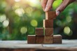 © pham - Close up of hand arranging wooden block into pyramid shape in business development and growth success process concept.