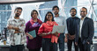 © Gorodenkoff - Group of Happy Multiethnic Indian Team of Female and Male Managers, Specialists and Business Professionals Posing for Camera and Smiling. Portrait of a Confident South Asian Team Leader Standing First