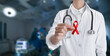 © New Africa - Cancer awareness. Doctor holding red ribbon on blurred background, closeup. Banner design with space for text