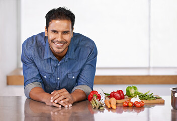 Man, smile and vegetables in kitchen for food, cooking and recipe for health indoor on mockup. Nutritionist or vegan with carrot, pepper and tomatoes with garlic for ingredient and vitamin