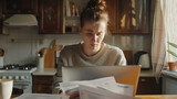 Fototapeta  - Stressed Young Woman looking at papers and bills with stressful face, Managing Finances with Laptop in Kitchen. Household budget, tax issue , late fees and penalties concept.