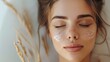 Close-up of a young woman with moisturizing cream on her face, with closed eyes and a serene expression, on a light background. Beauty and skincare concept.