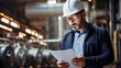 © Thanaphon - An electrical engineer wearing a safety helmet is inspecting technical blueprints at a hydroelectric power plant within a dam.