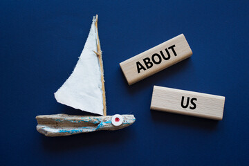 Wall Mural - About us symbol. Concept word About us on wooden blocks. Beautiful deep blue background with boat. Business and About us concept. Copy space